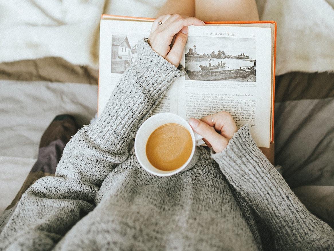 Person holding a book and drink.